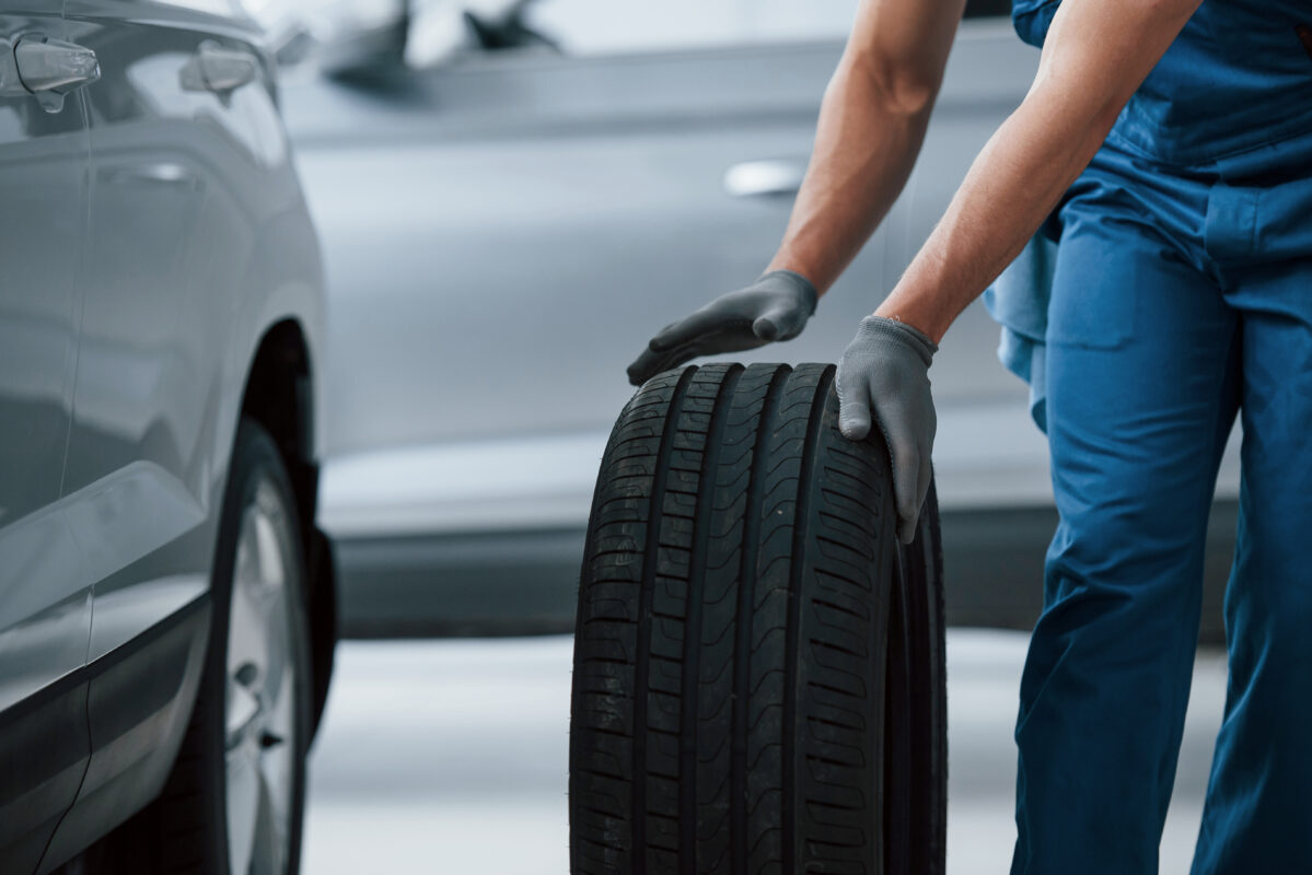 Business of car repairing. Mechanic holding a tire at the .repair garage. Replacement of winter and summer tires