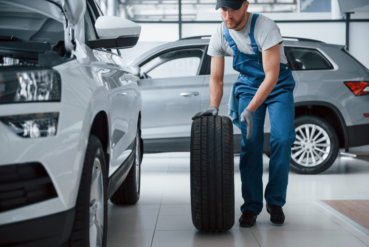 No big deal. Mechanic holding a tire at the repair garage. Replacement of winter and summer tires.